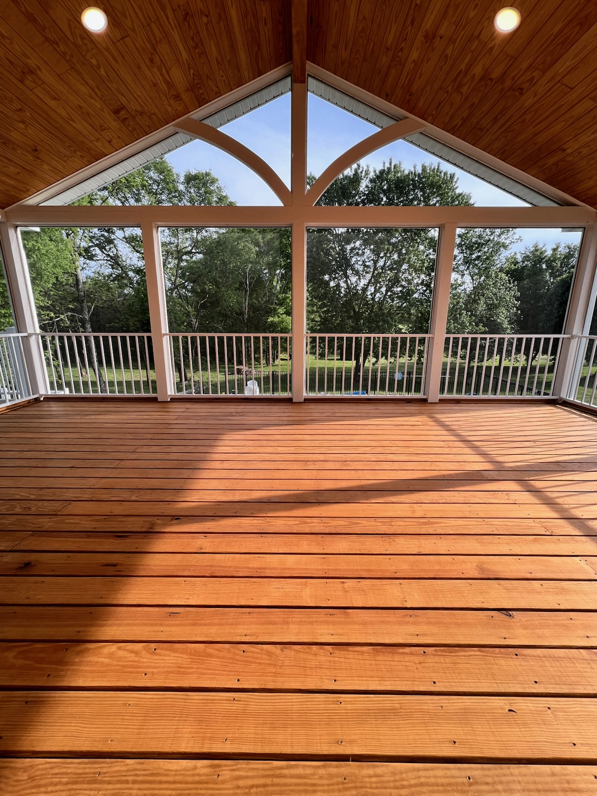 Custom screen porch with vaulted wood ceiling and stained deck by Clay Sickel Construction